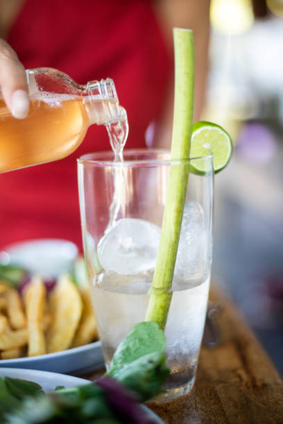 A tall glass filled with a refreshing beverage placed alongside a potted plant.
