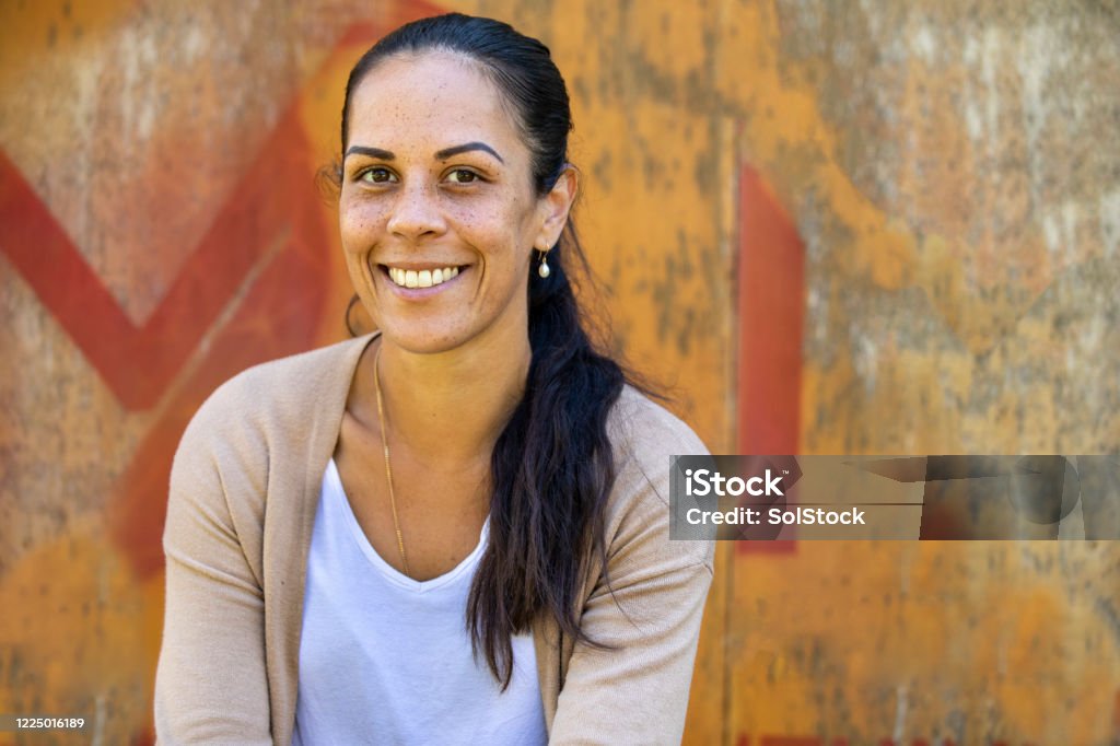 Happy Student Portrait of a happy young aboriginal woman on an industrial background. Aboriginal Peoples - Australia Stock Photo