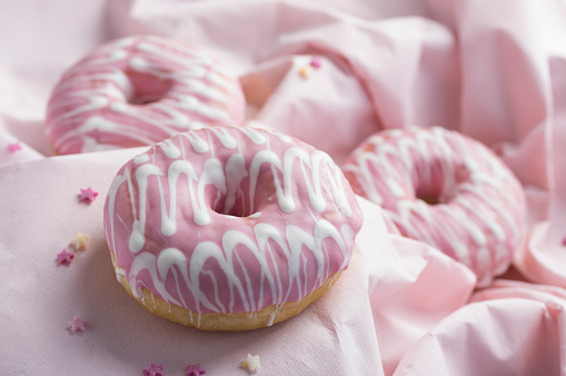 Pink glaze decorated donuts on wavy pink background in various focus