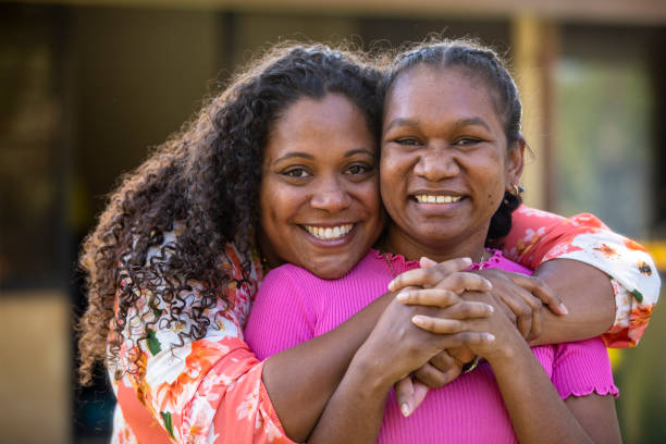 Friendship Two young aboriginal female students outdoors with their arms around each other smiling at the camera. aborigine woman stock pictures, royalty-free photos & images