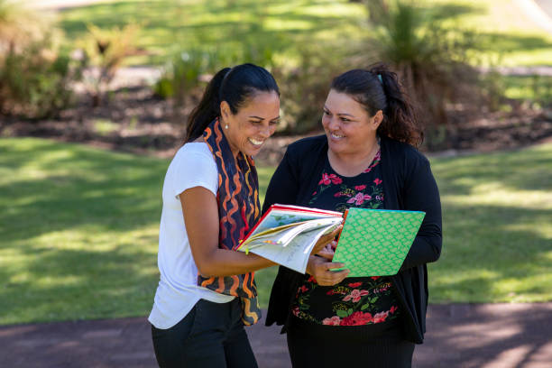 What Do You Need? Young aboriginal student talking to her tutor outdoors in the sun in Australia. aborigine woman stock pictures, royalty-free photos & images