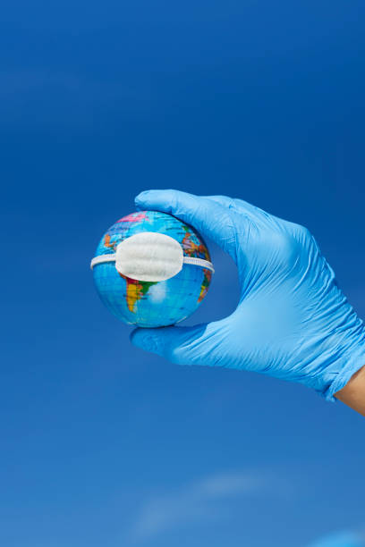 istock man wearing gloves showing a globe with a mask 1225019336