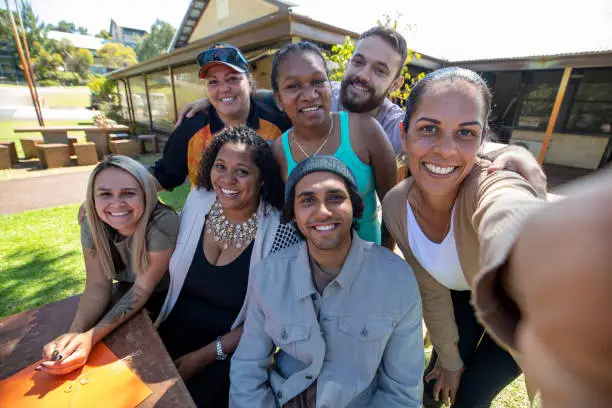 Young aboriginal students and their tutor taking a selfie together outdoors in Australia.