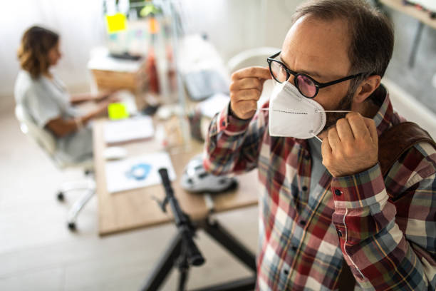 Businessman putting on face mask before leaving office