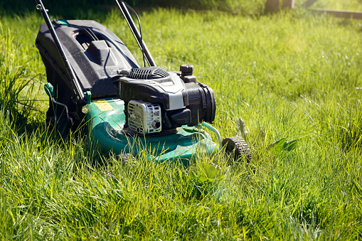 Senior man putting battery into electric cordless lawn mower