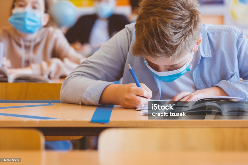 High school students at school, wearing N95 Face masks. High school students at school, wearing N95 Face masks. Sitting in a classroom and writing lessons. Education Stock Photo