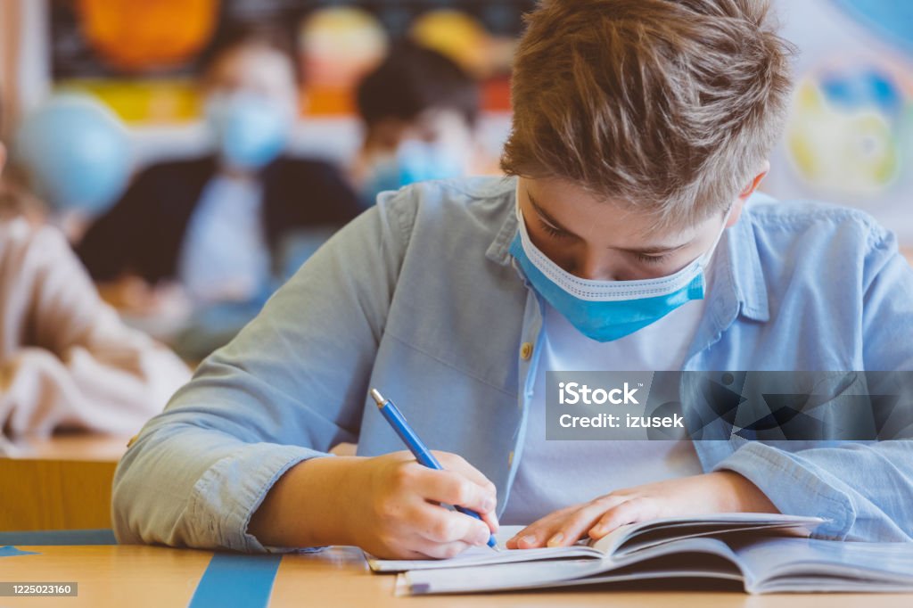 High school student at school, wearing N95 Face masks. High school student at school, wearing N95 Face masks. Sitting in a classroom and writing lessons. Classroom Stock Photo