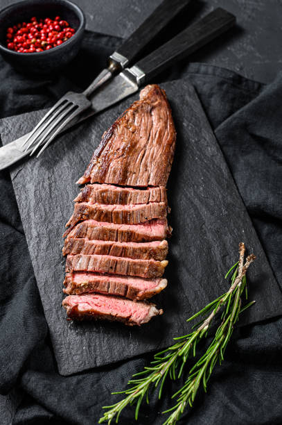 istock Roasted medium rare sliced flank beef steak. Black background. Top view 1225024513