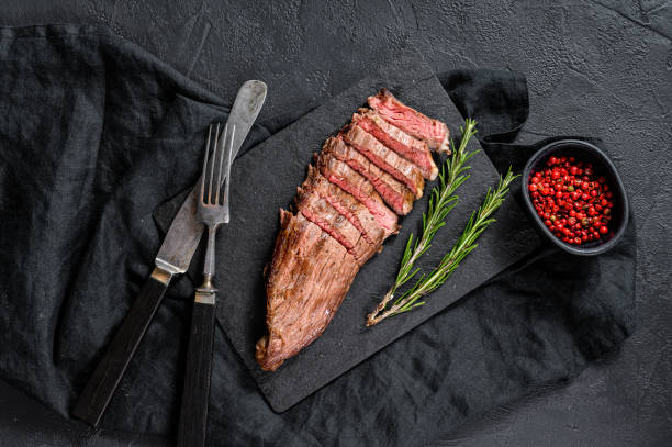 istock Steak of marbled beef roasting medium on a black stone Board. Black background. Top view 1225025396