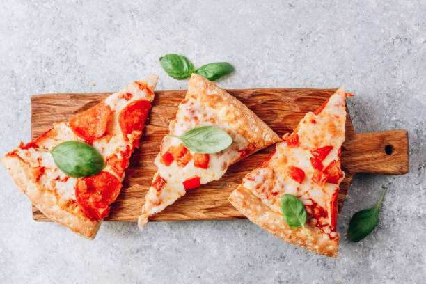 istock Slices pepperoni fresh pizza with basil on wooden board on a light gray background. Top view . With copy space 1225026736