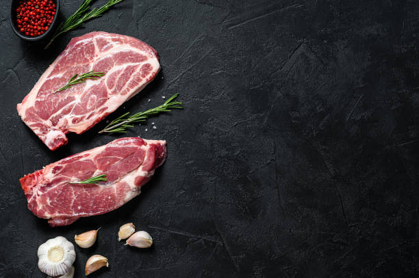istock Raw pork steak on the bone. Grilled meat. Black background. Top view. Space for text 1225031090