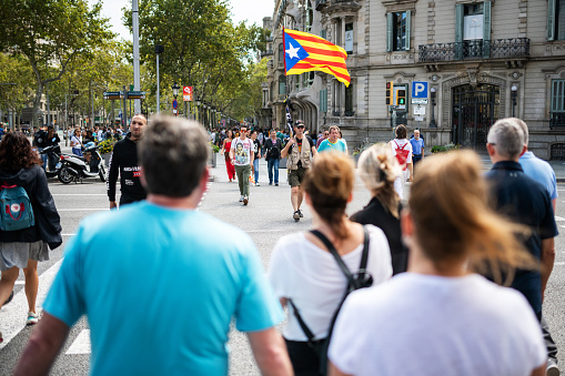 Barcelona, Spain - September 11, 2019: A man with a catalonia flag passes a street in Barcelona.