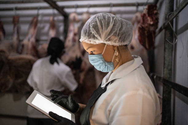 냉장 보관시 얼굴 마스크가 있는 디지털 태블릿을 사용하는 여성 정육점 - meat supermarket butchers shop market 뉴스 사진 이미지