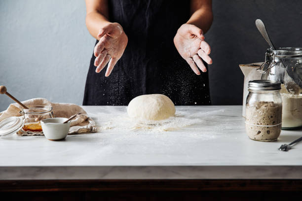 mulher jogando massa em farinha sobre balcão de mármore - dough kneading human hand bread - fotografias e filmes do acervo