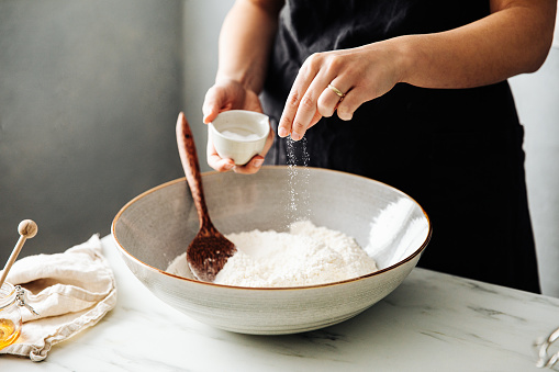 Mujer rociando sal en harina antes de mezclar photo