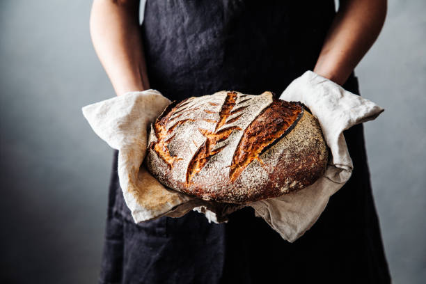 woman with fresh baked sourdough bread in kitchen - pao imagens e fotografias de stock