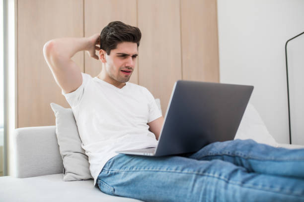 istock Portrait of angry irritated man using laptop while sitting on sofa at home 1225038861