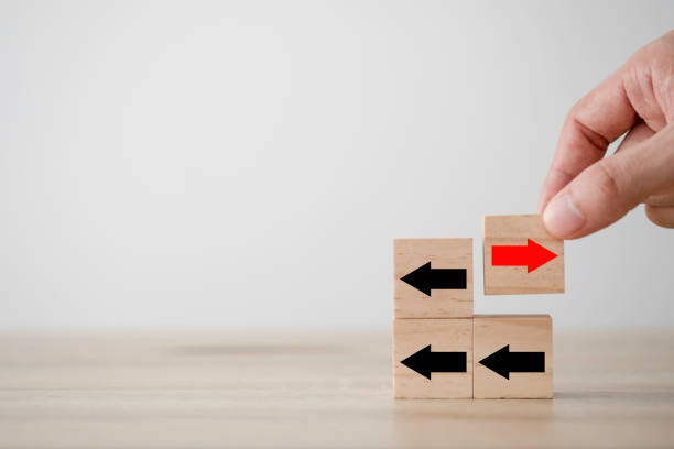 istock Hand putting red arrow on wooden cube which opposite direction with black arrow. Disruption and different thinking for discovery new technology  and new business opportunity concept. 1225039237