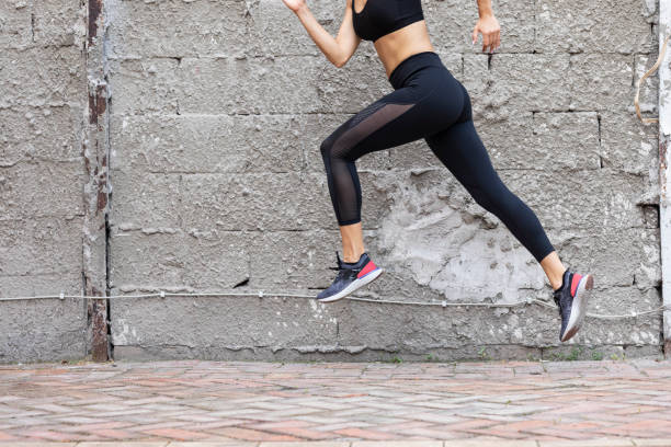Fit Woman in Black Sportswear Running Outdoors Active lifestyle: a fit woman runner during her morning running workout. hot women working out pictures stock pictures, royalty-free photos & images