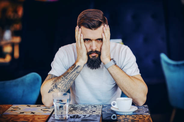 istock Young desperate bearded tattooed muscular handsome hipster holding hands on face and looking at camera. He is waiting for his girlfriend. 1225040829