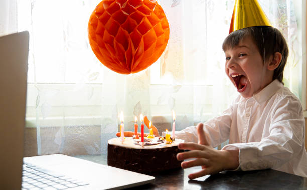 Cheerful boy in mask celebrates his birthday remotely during quarantine Glad and happy boy make distance call to his friends and celebrates his birthday remotely during a pandemic and self-isolation virtual birthday celebration stock pictures, royalty-free photos & images
