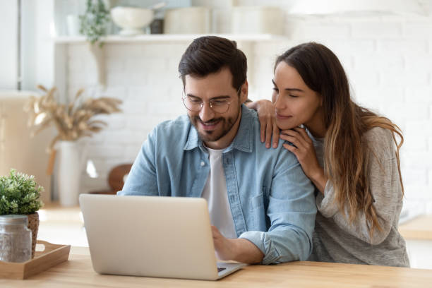 istock Happy young man and woman hugging, using laptop together 1225046277