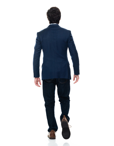 Rear view of aged 20-29 years old with short hair caucasian young male business person walking in front of white background wearing button down shirt