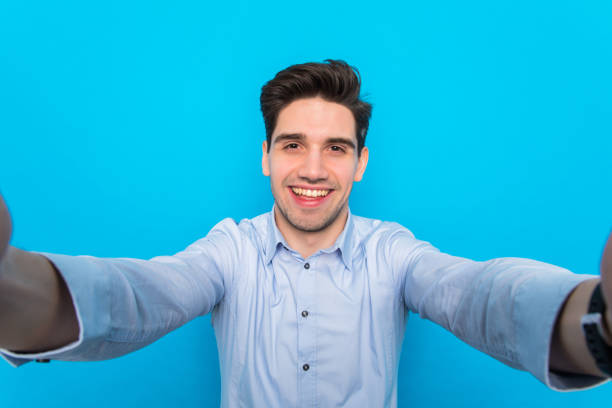 istock Handsome young man is making selfie and smiling on blue background 1225051537