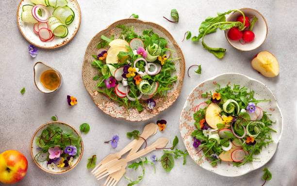 Delicious summer salad with edible flowers, vegetables, fruit, microgreens and cheese. Delicious summer salad with edible flowers, vegetables, fruit, microgreens and cheese. Clean and healthy eating concept. Top view. salad fruit lettuce spring stock pictures, royalty-free photos & images
