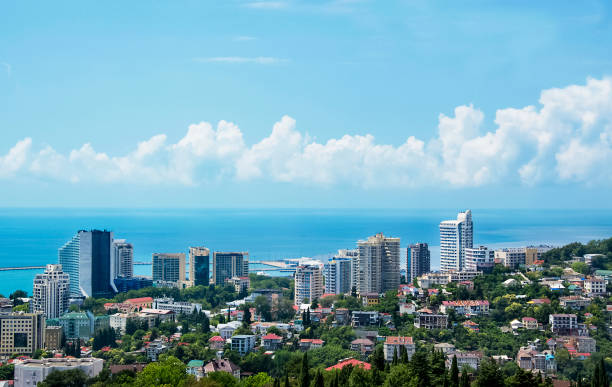 View of blue coast of Black Sea in Sochi with houses under summer blue sky. Sochi, Russia, 2019/06/24 View of blue coast of Black Sea in Sochi with houses under summer blue sky. Sochi, Russia, 2019/06/24 sochi photos stock pictures, royalty-free photos & images