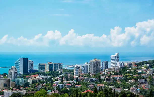 View of blue coast of Black Sea in Sochi with houses under summer blue sky. Sochi, Russia, 2019/06/24