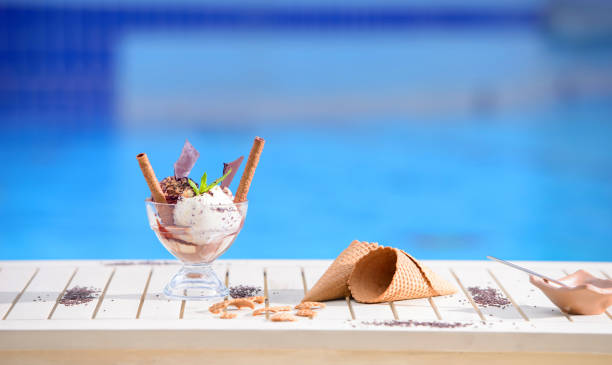 istock Glass with mint ice cream scoops on blur bokeh background with copy space. Waffle cones on white table top of blue water pool 1225055790