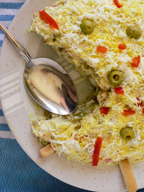 istock Russian salad with olives, red pepper, grated egg with mayonnaise. Serving spoon on blue tablecloth 1225055807