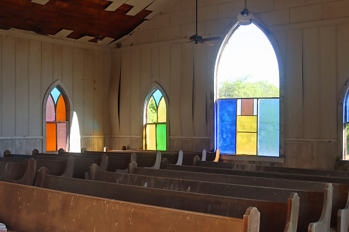 Abandoned, old church with stained glass and pews in poor condition
