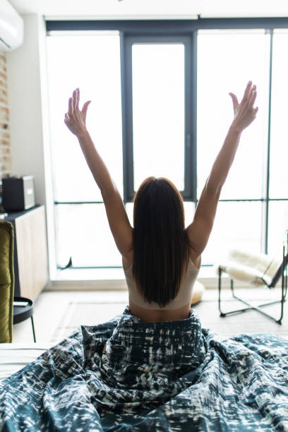 istock Young woman stretching in bed after wake up, back view 1225058937