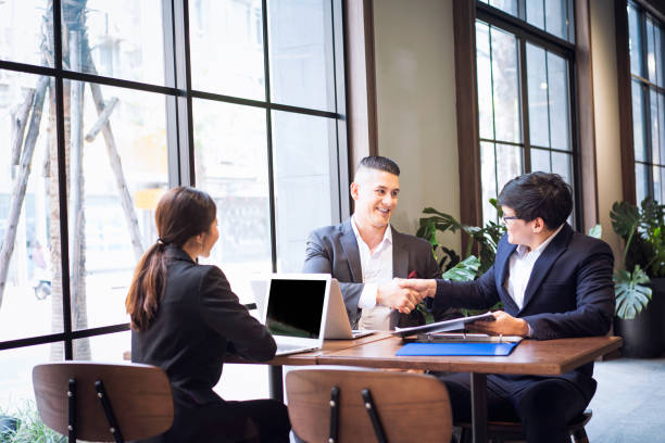 istock Co-working space concept. Business cooperation and handshake. The young manager is encouraging and appreciating his colleagues. 1225061302