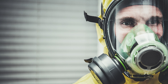 Close Up Of Caucasian Man Standing Observing And Wearing Hazmat Suit And Gas Mask.