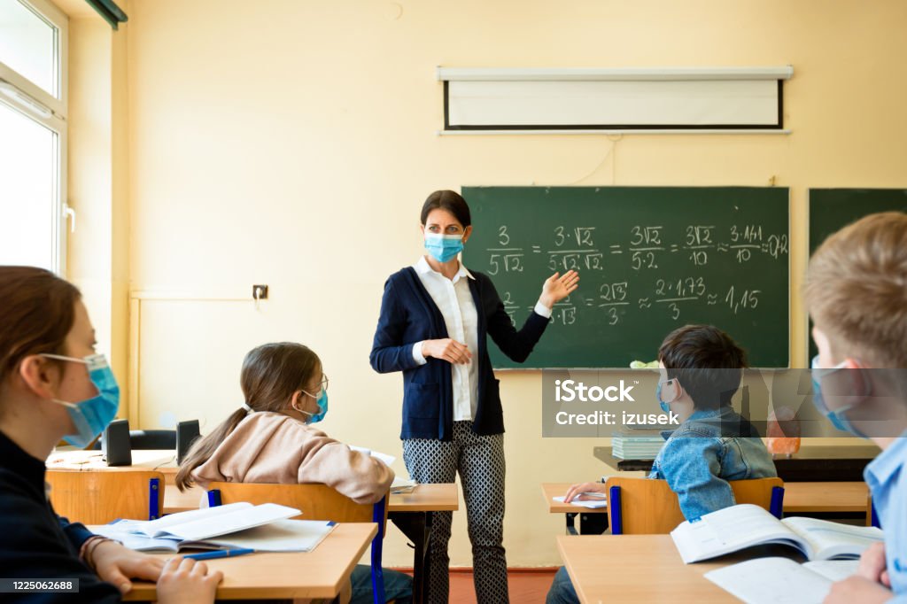 Covid-19. A teacher teaches mathematics A teacher wearing a N95 Face masks teaches mathematics at an High School Teacher Stock Photo
