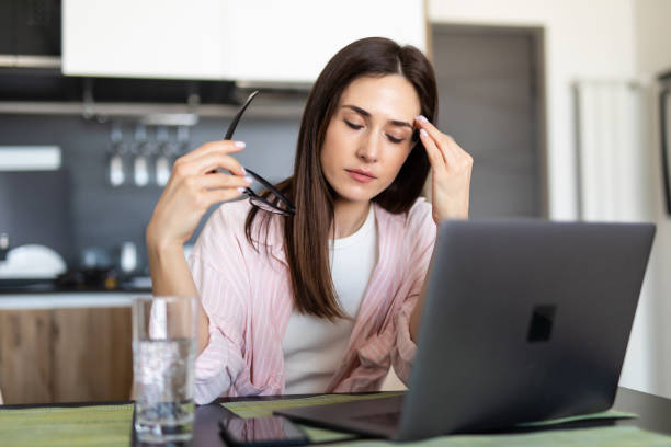 istock Young woman having headache while working on laptop sitting at her kitchen table at home. 1225062831