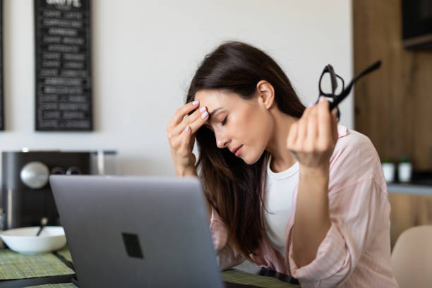 istock Attractive tired young woman working with laptop while sitting at the kitchen 1225064222
