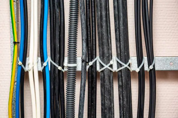 Cables fastened with white ties on the cable ladder. Ground wires, corrugated cable. Cable management. Close-up. Horizontal orientation. High quality photo.