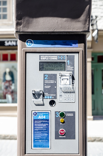 Public parking payment station on the side of street downtown Old Quebec city during day of springtime
