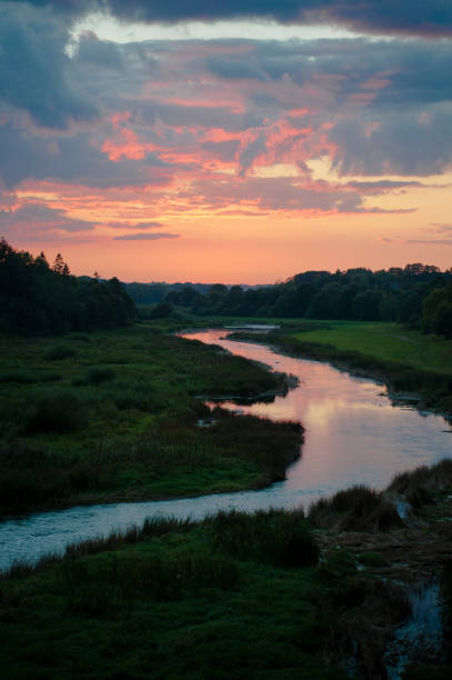 Beautiful sunset over a river with green bushes and color rich sky
