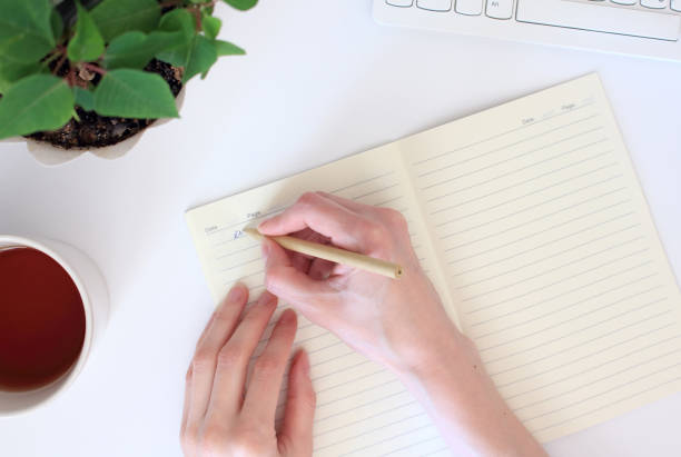 istock Top view of a young woman writes a day plan in a diary, sitting at a workplace with a computer. Home schooling, working at home concept 1225067657