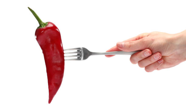 istock Close up female holds in hand fresh red pepper on fork isolated on white background. Proper nutrition, vegetarian food, healthy lifestyle, vegetable concept. 1225067658