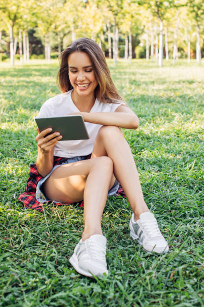 istock Woman sitting at the park using a tablet 1225067827