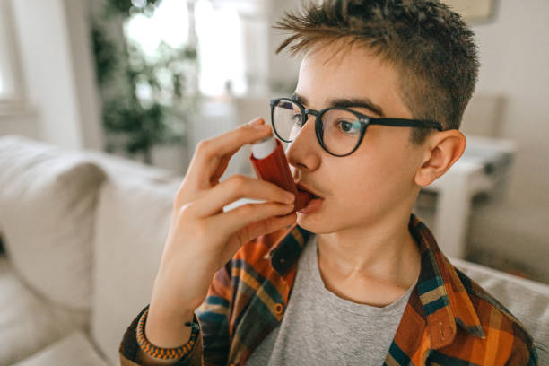 Teenager boy using asthma inhaler Teenager boy using asthma inhaler at home air attack photos stock pictures, royalty-free photos & images