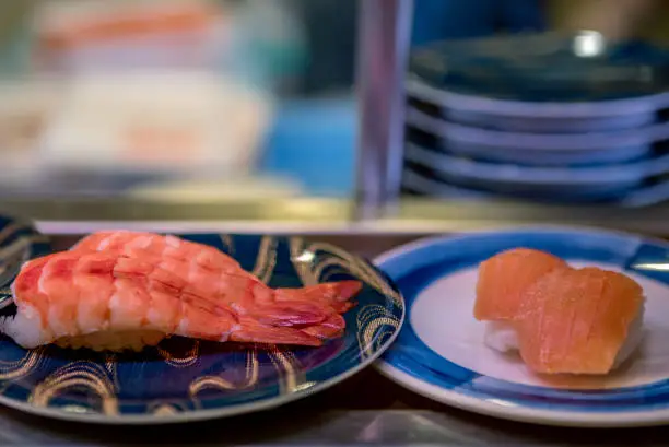 Photo of Sushi on conveyor belt in Japan restaurant. Sushi train is a Japanese fast food