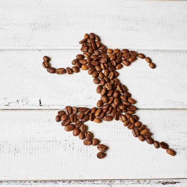 бегущий мужчина собрался из жареных кофейных зерен на белой деревянной поверхности - кофеин стоковые фото и изображения