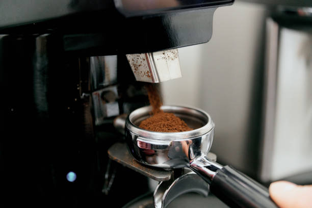 o processo de moagem automática de café em um moedor de café close-up. um punhado de café moído no suporte - grinding - fotografias e filmes do acervo